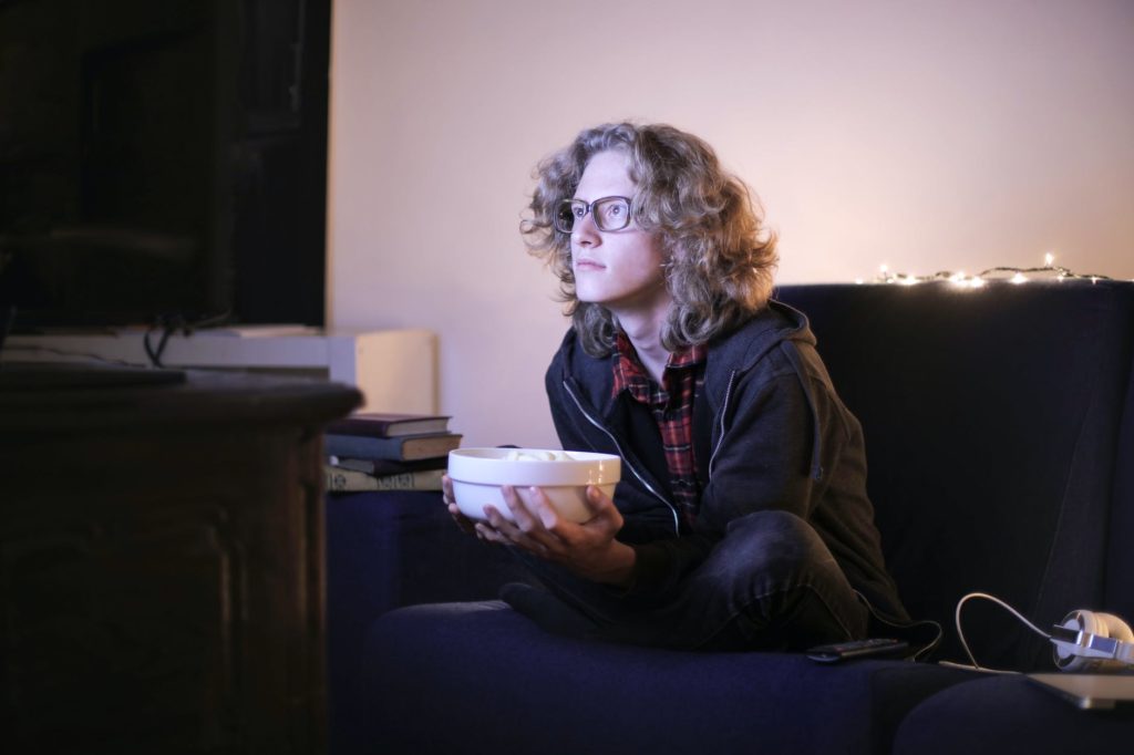 focused man with bowl of popcorn watching tv at home