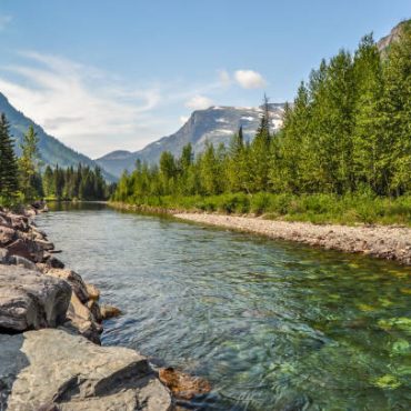 A river runs calmly through a valley in Glacier National Park of Montana.