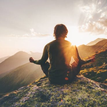 Man meditating yoga at sunset mountains Travel Lifestyle relaxation emotional concept adventure summer vacations outdoor harmony with nature